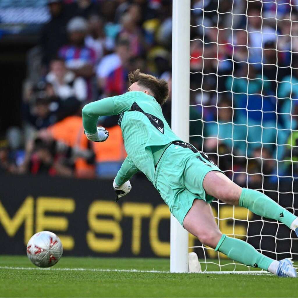Crystal Palace goalkeeper Dean Henderson dives to his right to save a penalty.