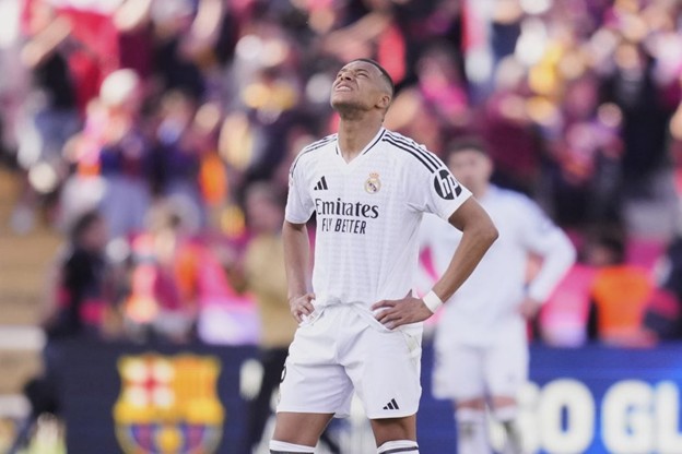 Mbappé looks frustrated with his head tilted back and hands on hips during a match.