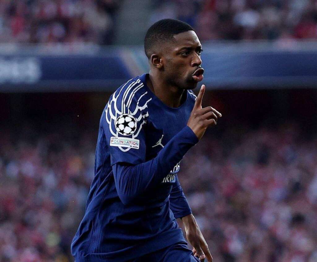 PSG's Ousmane Dembélé celebrates after scoring in a UEFA Champions League match, signaling for silence.
