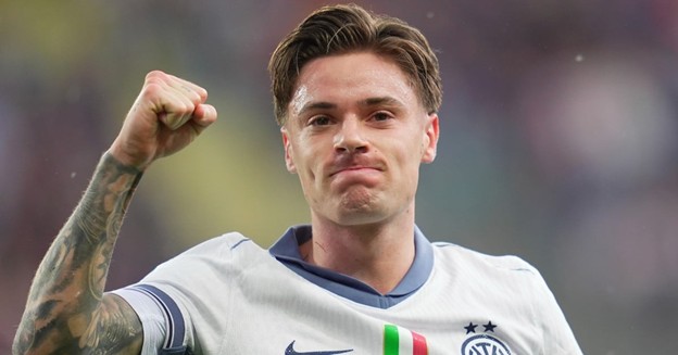 Inter Milan player celebrates with a clenched fist and a confident expression, wearing the team's white away kit with the Italian flag stripe on the chest.