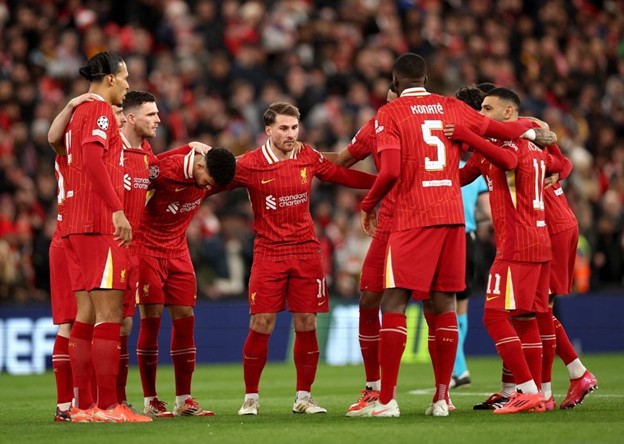 Liverpool FC players unite in a pre-match huddle during a UEFA Champions League game at Anfield, showcasing team spirit and unity.