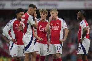 Arsenal players look dejected and discuss on the pitch after conceding during a UEFA Champions League match.