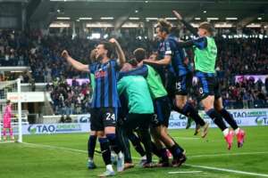 Atalanta players celebrate passionately on the field after a crucial goal or victory.